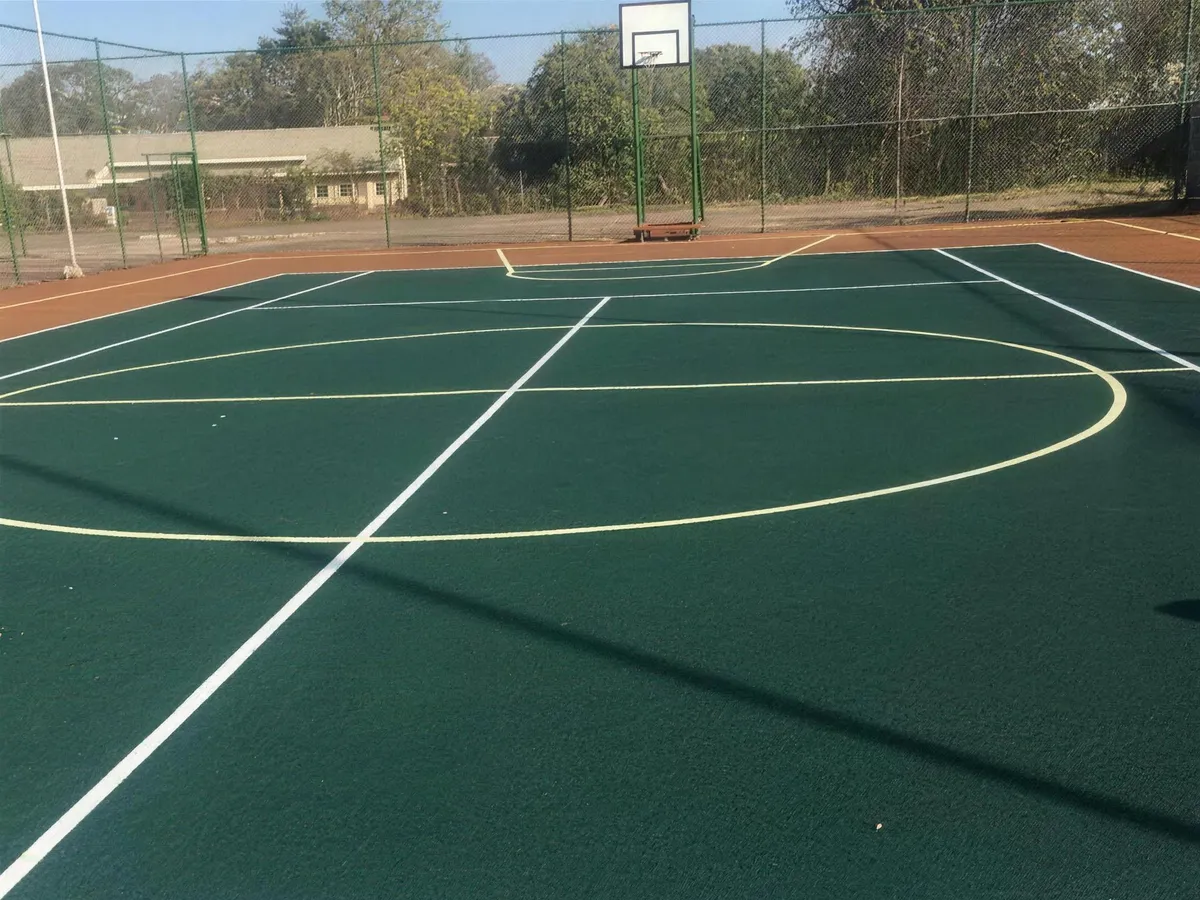 Resurfaced green outdoor basketball court with freshly painted lines and hoop, built by Real Tennis Court