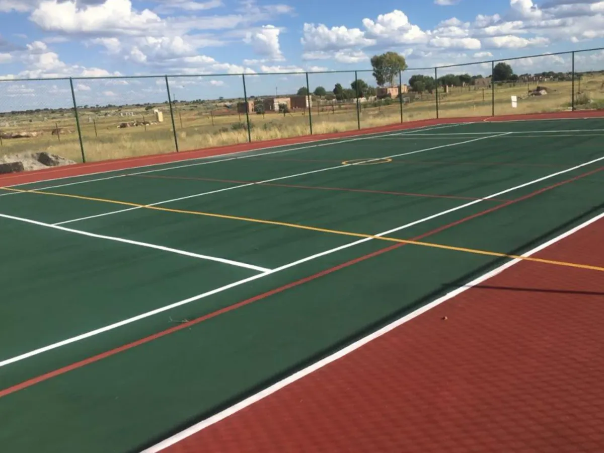 Resurfaced green multi-sport court with netball thirds and centre circle marked in yellow, built by Real Tennis Court